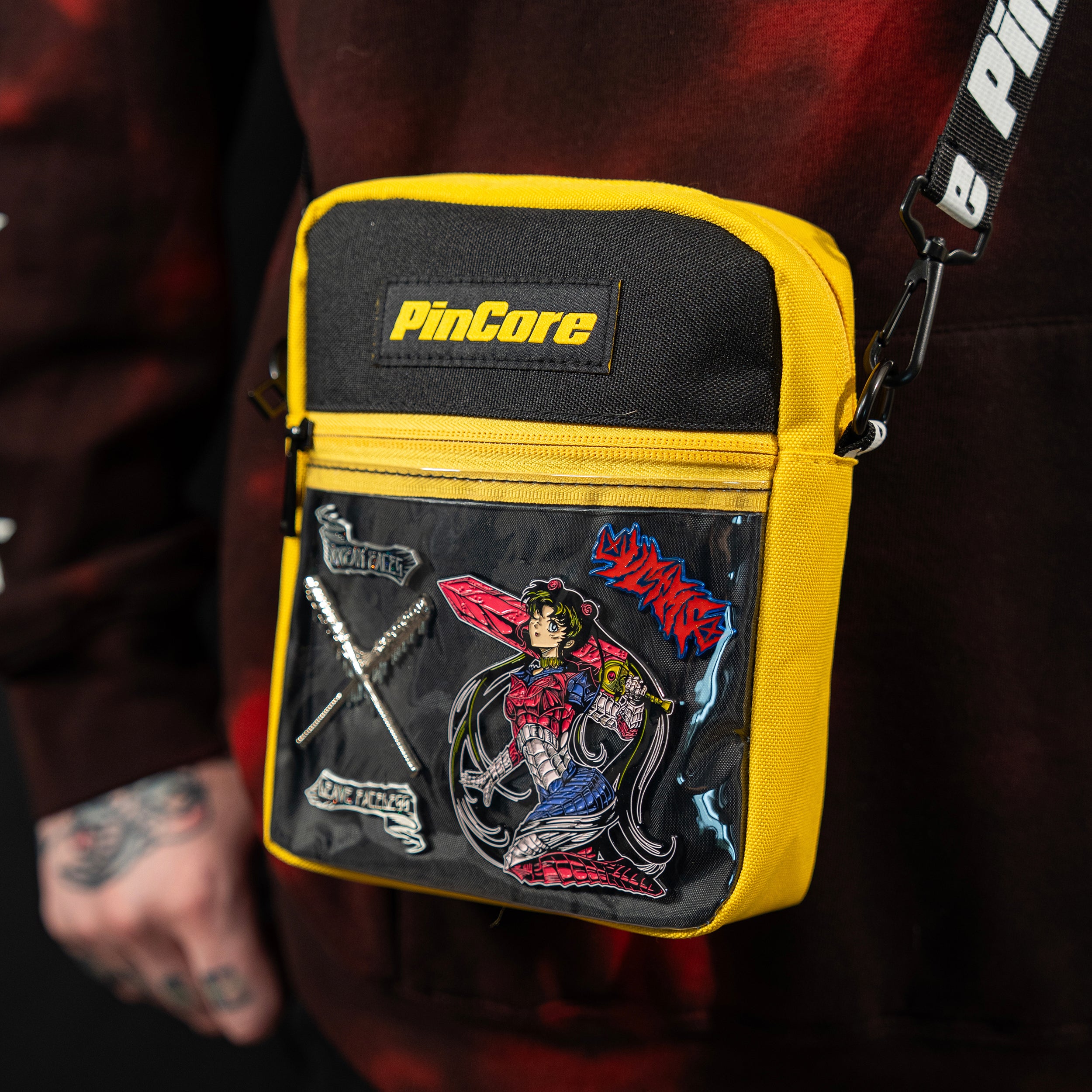 Image of Pincore yellow and black pin display shoulder bag with clear front pocket showing enamel pins