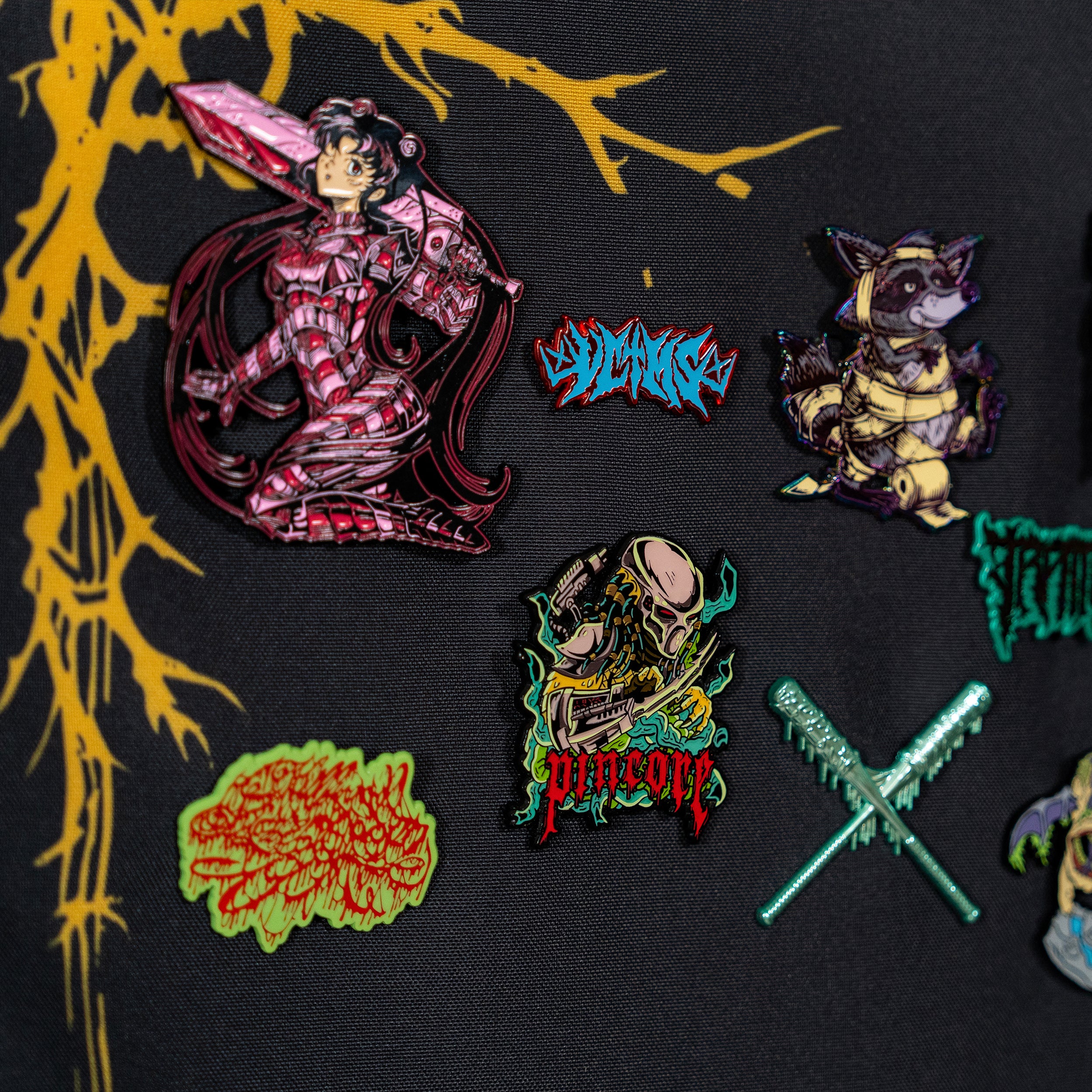 Image of Pincore Merchandise enamel pins on a black hanging pin display board showing anime and creature designs