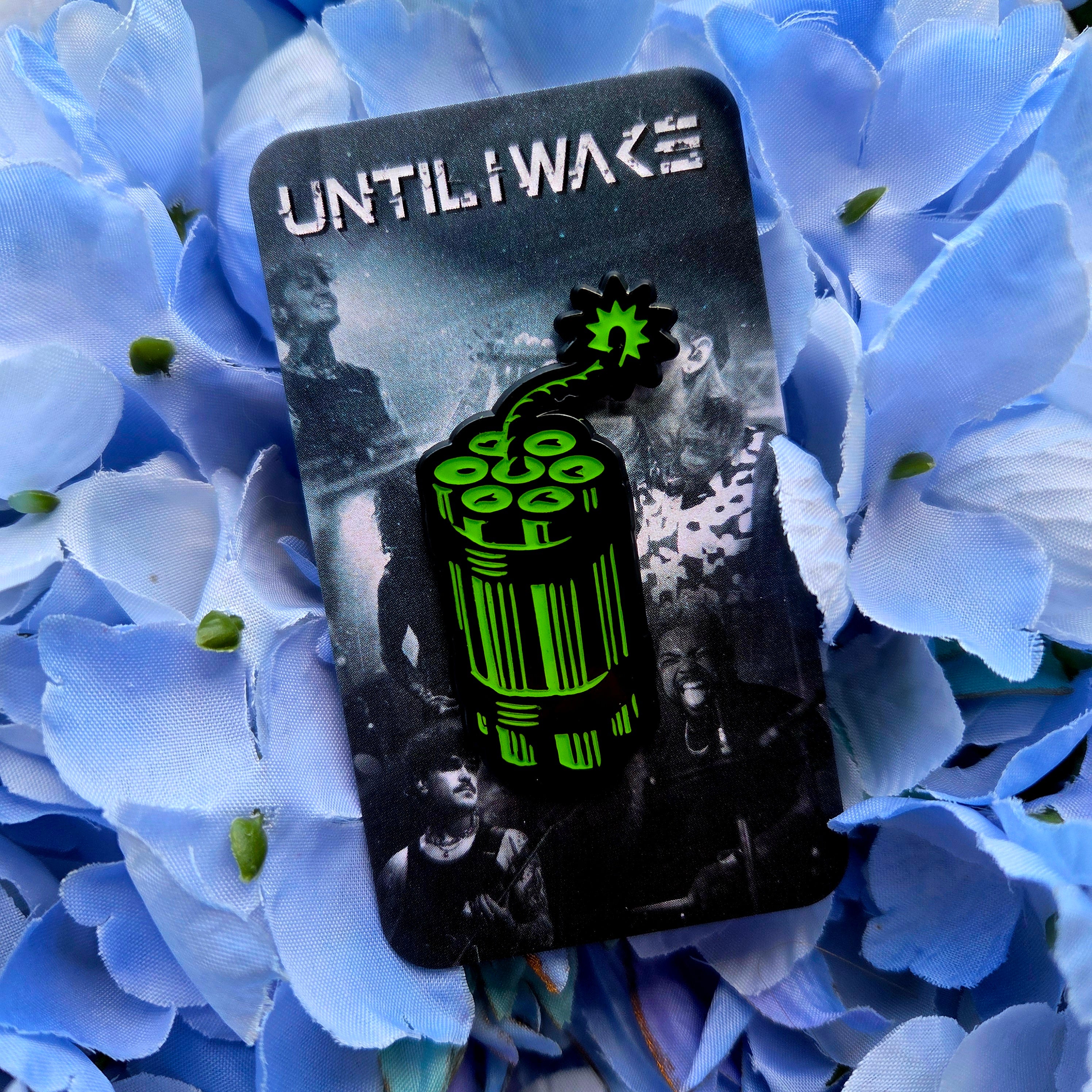 Until I Wake enamel pin green dynamite design on band photo backing card on blue floral background